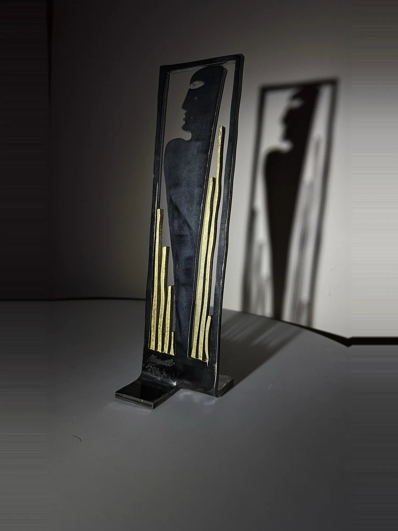 Steli, sculpture de Gianluca Magnelli, un profil entre des tiges dorées.